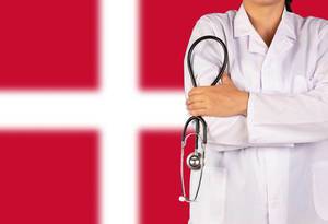 Dänisches Gesundheitssystem symbolisiert durch die Nationalflagge und eine Ärztin mit Stethoskop in der Hand