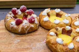 Danish pastries with raspberries and sugar icing on a wooden board