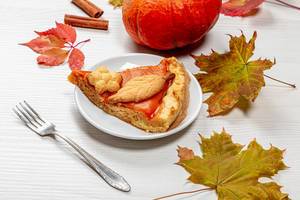 Das Konzept des Abendessens an Thanksgiving - herbstlich geschmückter Tisch mit einem Stück Kürbiskuchen