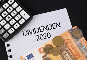Das Konzept von Dividenden 2020: Dividenden 2020 Text auf einem Blatt Papier mit einigen Münzen, einem 5-Euro Schein und einem Kalkulator