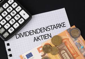 Das Konzept von Dividendenstarke Aktien: Dividendenstarke Aktien Text auf einem Blatt Papier mit einigen Münzen, einem 5-Euro Schein und einem Kalkulator