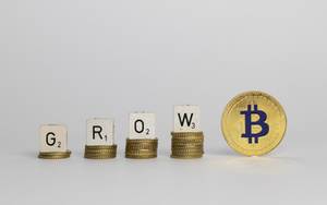 Das Wachstum des Bitcoins - Die Buchstaben GROW auf höher werdenden Münzenstapel und eine goldene Bitcoin-Münze