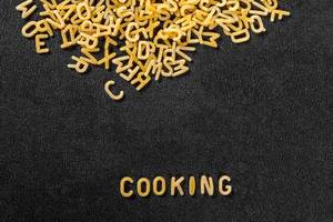 Das Wort Cooking, geschrieben mit Pasta, vor schwarzem Hintergrund