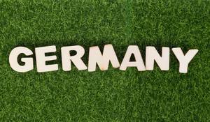Das Wort GERMANY (Deutschland) aus Buchstaben aus weißem Holz auf Fussball-Wiese