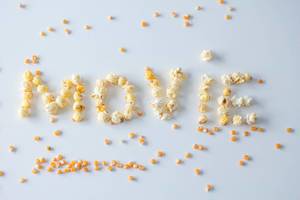 Das Wort ‘Movie’ geschrieben mit Popcorn vor weißem Hintergrund