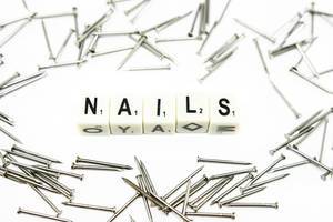 Das Wort NAILS gebildet aus Würfeln mit Buchstaben zwischen verteilten Nägeln