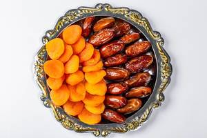 Dates and dried apricots on a tray on a white background. Top view