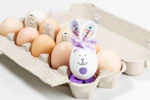 Decorated rabbit-egg in a box with chicken eggs