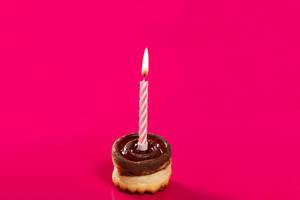 Delicious birthday cupcake with candle on pink background