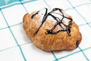 Delicious fresh pastry croisant with chocolate and powdered sugar