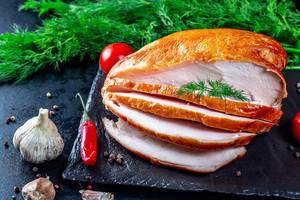 Delicious slicing of smoked chicken fillet with spices on a dark background