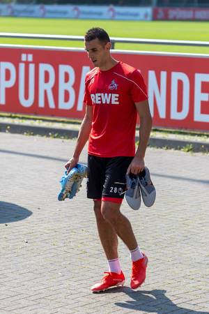 Der Kölner Fußballspieler Ellyes Skhiri läuft nach dem Training mit Fußballschuhen über das Gelände vorm Mannschaftsclubhaus