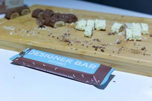 Designer Bar Proteinriegel mit Kokosnuss-Geschmack auf einem Holzbrett auf der Fibo in Köln