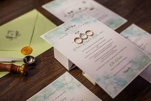 Details von Hochzeitseinladung mit Einladungsschreiben, Trauringen, Umschlag und Wachssiegel