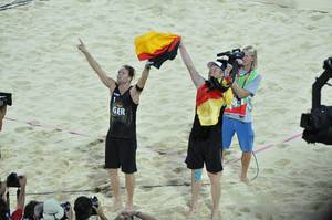 Deutsche Beach-Volleyball-Spieler mit deutscher Flagge in Händen