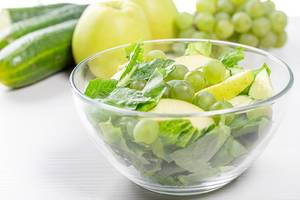 Diäten-Salat mit grünen Salatblättern, Äpfel und reifen Weintrauben, in einer Glaschschale