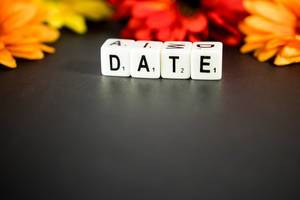 Dice reading DATE with flowers on the background