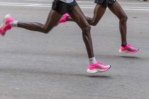Die Beine von zwei Tempomachern in pinken Nike ZoomX Vaporfly Next% Laufschuhen beim Chicago Marathon 2019