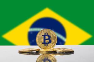 Die Flagge Brasiliens mit einem Set aus vier goldenen Bitcoins im Vordergrund