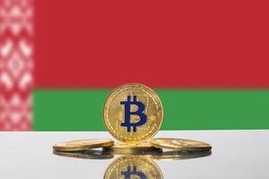 Die Flagge Weißrusslands hinter einem kunstvollen Arrangement aus vier goldenen Bitcoins