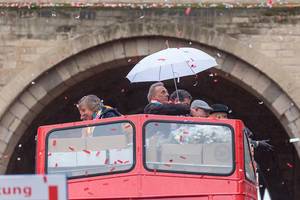 Die Mitglieder der Bläck Fööss mit Regenschirm auf dem Deck vom Doppelstockbus, der als Wagen für ihr 50-jähriges Jubiläum beim Rosenmontagsumzug in Köln dient