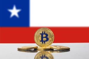 Die Nationalflagge Chiles mit vier goldenen Bitcoin-Münzen im Vordergrund
