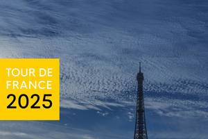 Die Spitze des Eiffelturms vor bewölktem Himmel und neben der Aufschrift "Tour de France 2025", für das erfolgreiche Radsport-Event in Frankreich