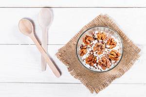 Diet cheese dessert with nuts and seeds on a white background with wooden spoons (Flip 2019)