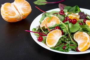 Diet salad with spinach, tangerine and cranberries on a black background (Flip 2019)