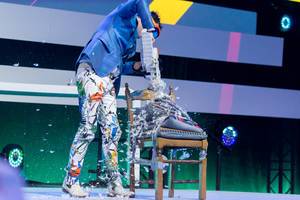 Dietmar Dahmen saws pillows on a chair at his stage show of Digital X 2019 in Cologne