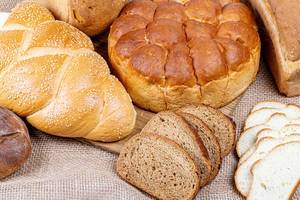 Different kinds of fresh bread on burlap background, top view (Flip 2020)