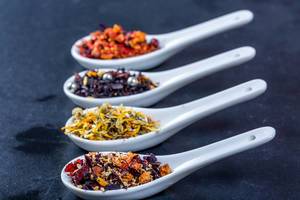 Different varieties of dried tea in ceramic spoons