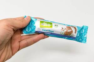DM Bio-Milkchocolate coconutbar in packaging held by male Hand