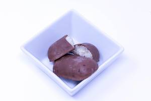 DM Bio-Vollmilch-Schokoladen-Kokosriegel in quadratischer Schale auf weißem Hintergrund