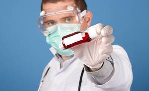 Doctor holding blood sample tube on blue background