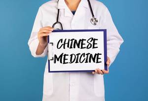Doctor holding clipboard with Chinese medicine text