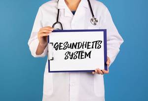 Doctor holding clipboard with Gesundheits System text