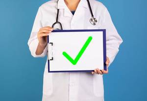 Doctor holding clipboard with green check mark