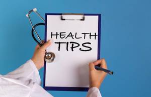 Doctor holding clipboard with Health tips text