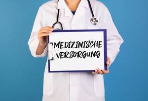 Doctor holding clipboard with Medizinische Versorgung text