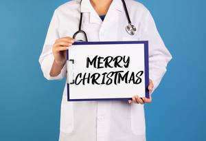 Doctor holding clipboard with Merry Christmas text