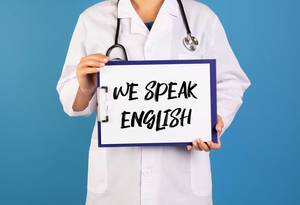 Doctor holding clipboard with We speak English text