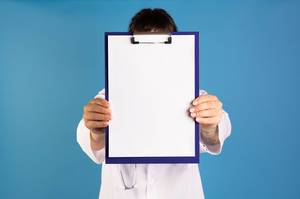 Doctor showing blank clipboard on blue background