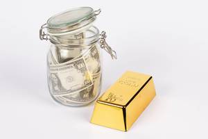 Dollar bills in glass jar with gold bar on white background