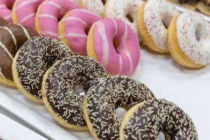 Donuts with different toppings, with dark chocolate, pink and white icing and patterns on white tray