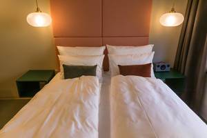 Doppelbett mit bunten Kissen im Zimmer vom Jams Music & Design Hotel in München, Bayern