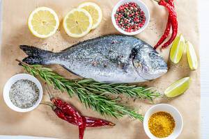 Dorado fish is prepared for baking on parchment paper with ingredients (Flip 2019)