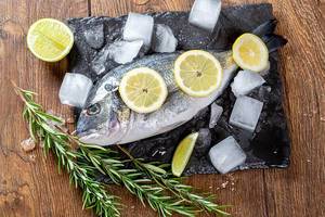 Dorado or sea bream fish with lime and lemon slices and sprigs of rosemary. Mediterranean cuisine. Top view