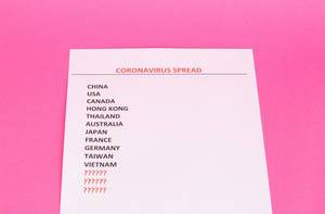 Draufsicht einer Liste mit Coronavirus betroffenen Ländern auf pinkem Hintergrund