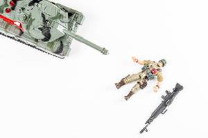 Draufsicht Panzer und Spielfigur eines auf dem Boden liegenden Soldaten auf weißem Hintergrund - Konzept des Todes